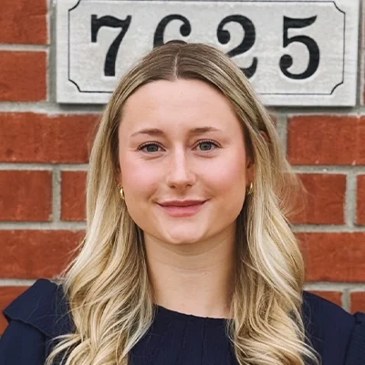 Receptionist Avery Smiling In Front Of Brick Wall