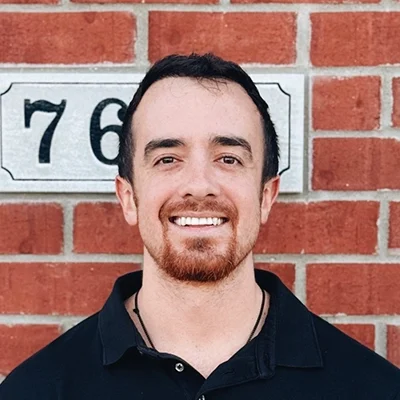 Chiropractic Intern James Smiling In Front Of Brick Wall